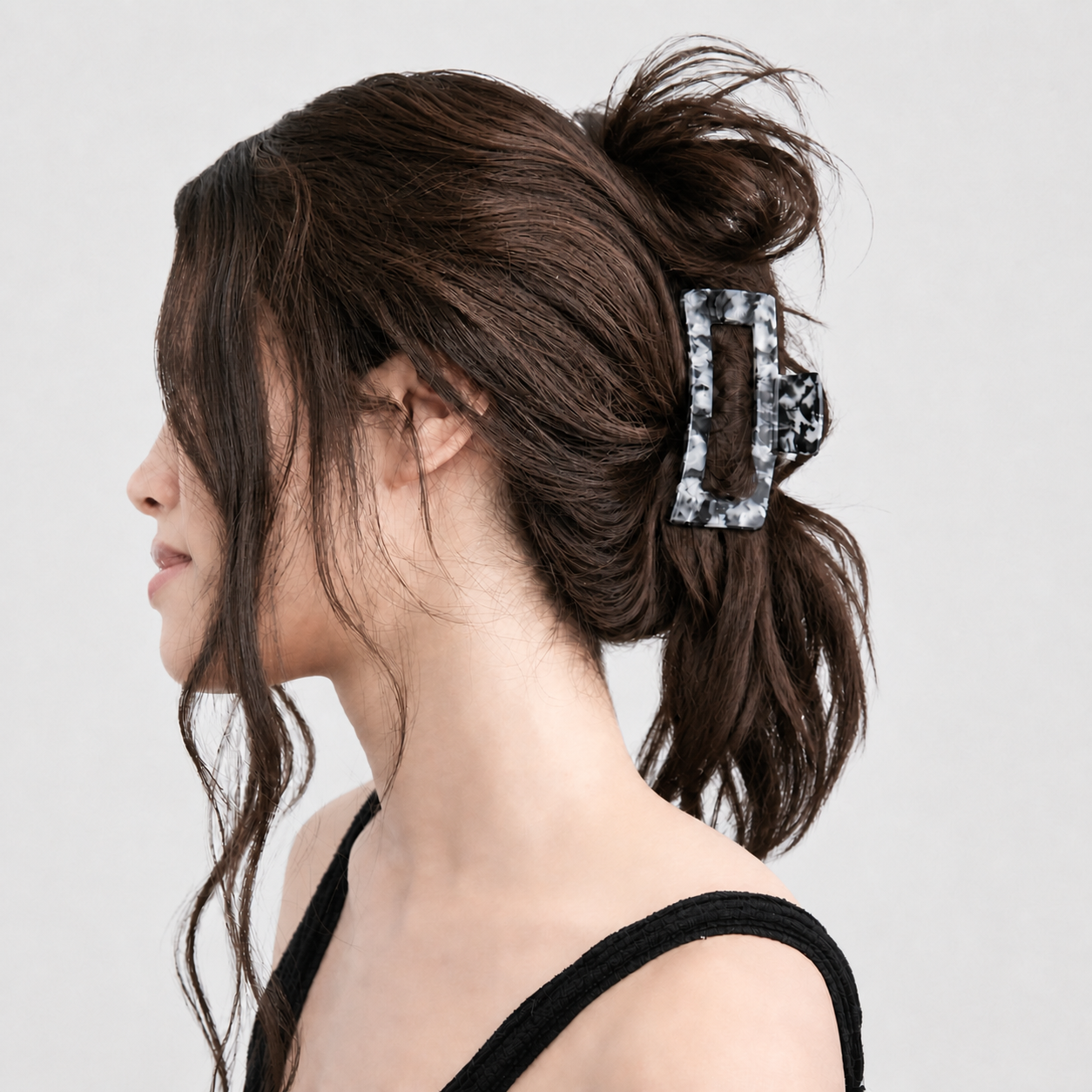 Brunette model whose hair is not fully held by a standard claw clip